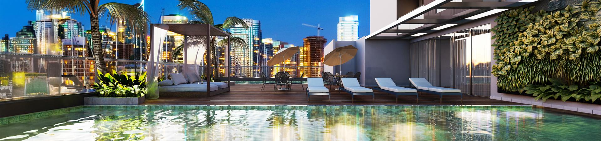 Rooftop pool area at dusk with city skyline, palm trees, cabanas, lounge chairs and patio tables on a wooden deck.