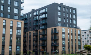 Modern apartment complex with dark gray and tan façades and multiple balconies throughout the buildings.