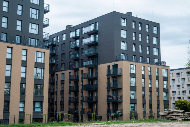 Modern apartment complex with dark gray and tan façades and multiple balconies throughout the buildings.