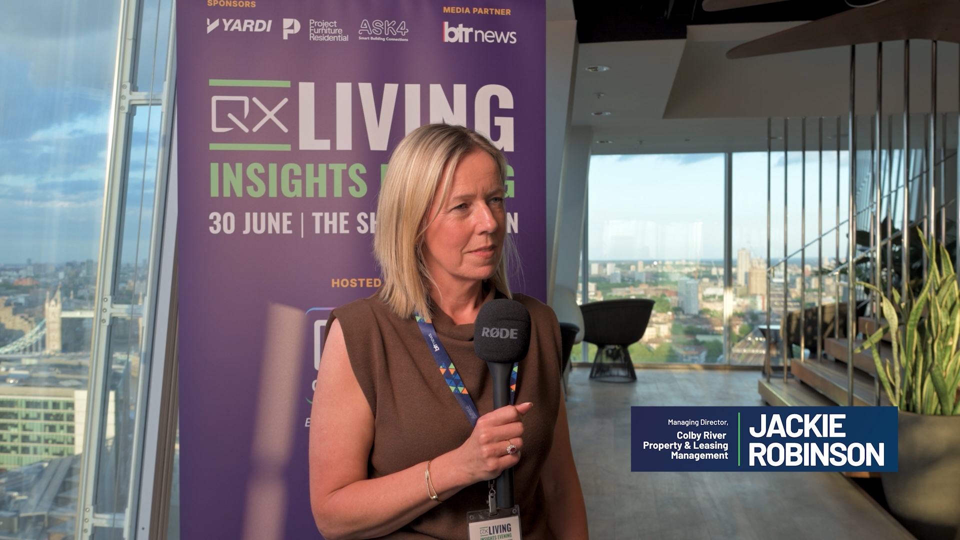 Woman being interviewed holds a microphone, with a purple 'LIVING INSIGHTS' banner behind her and city windows in the background.